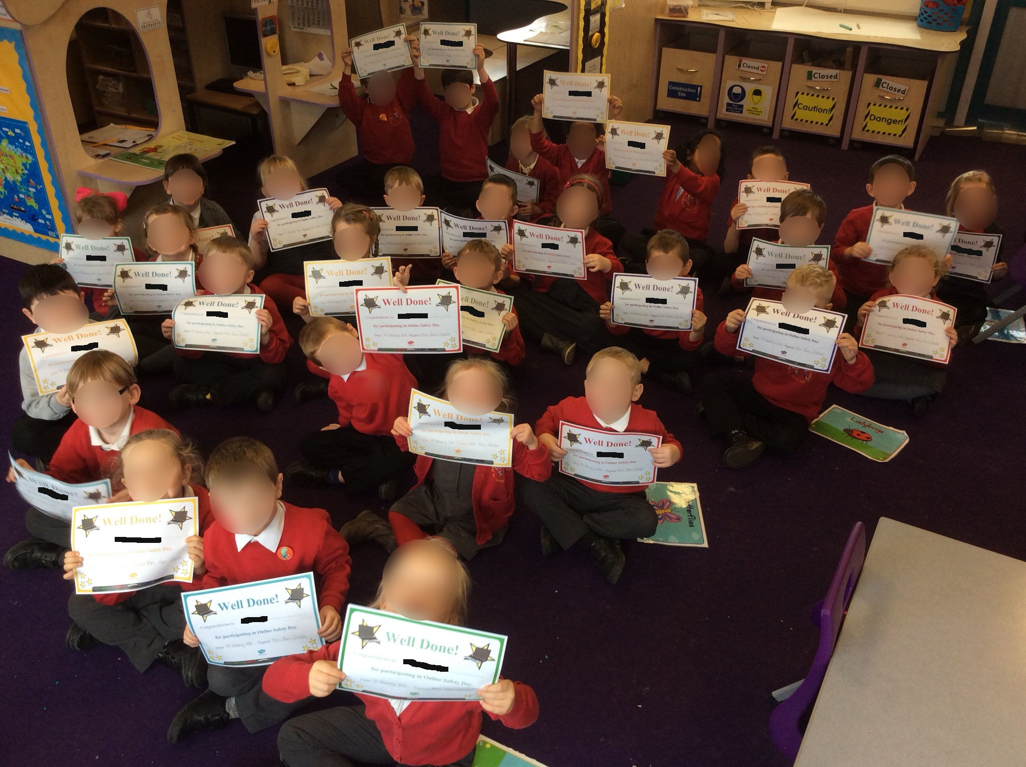 A class of 5 & 6 year olds holding up certificates for online safety day